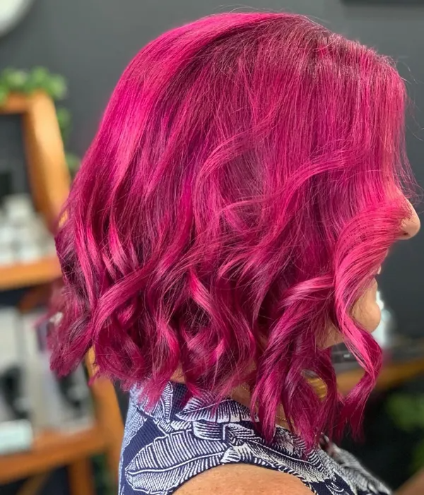 Side view of shoulder-length vivid pink wavy hair with curled ends