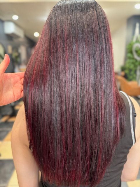 Close-up of wavy magenta and purple hair with teal highlights, viewed from behind.