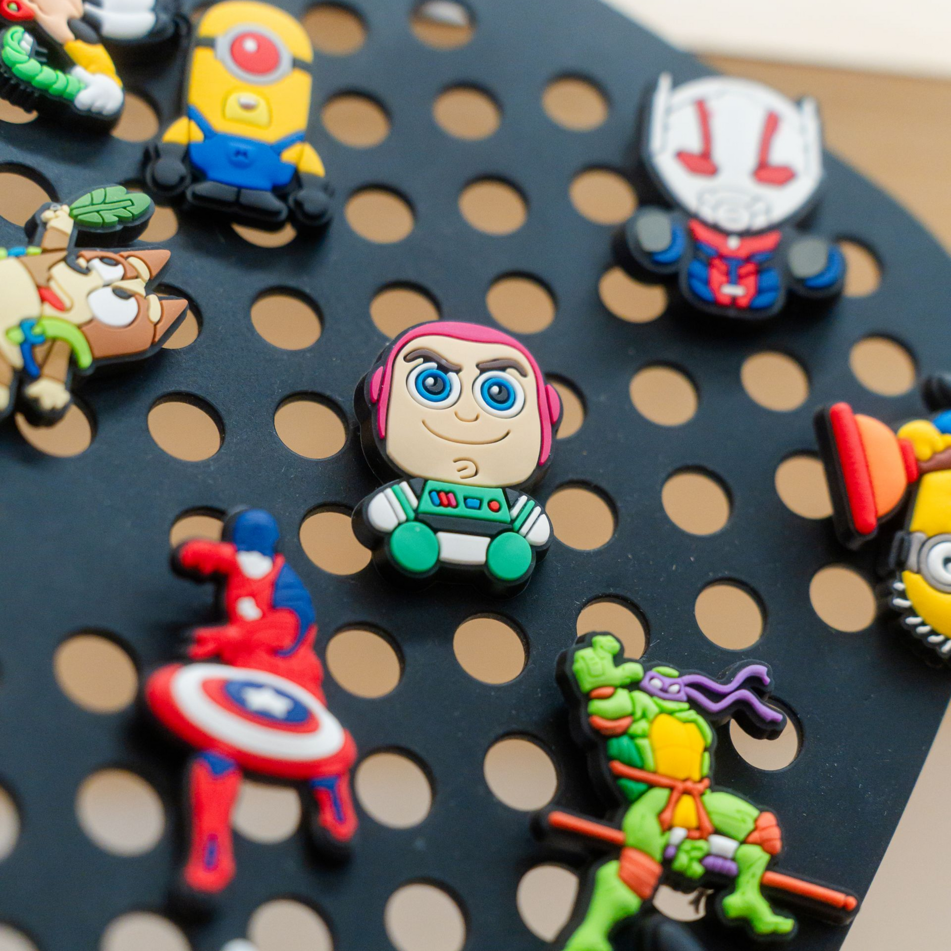 Assorted colorful superhero and cartoon pins on a black pegboard