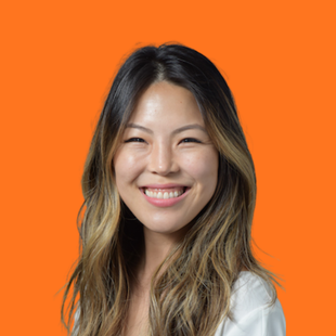 Smiling woman with long wavy hair against a bright orange background