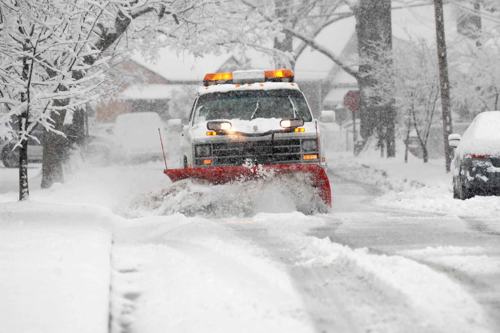 Snowplow clearing a snowy street, pushing deep snow under a winter storm.