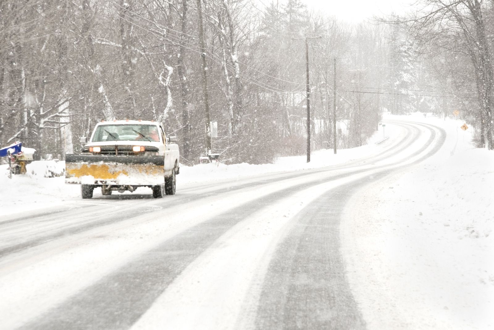 Pickup truck driving on a snowy road with heavy snowfall and tire tracks