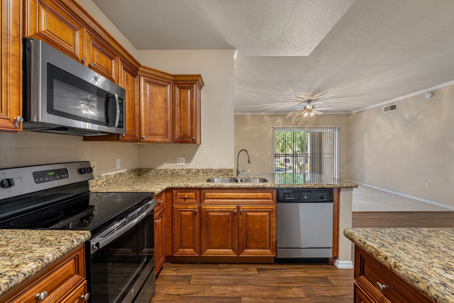 Modern kitchen with wood cabinets, granite counters, stainless appliances, and a windowed dining area