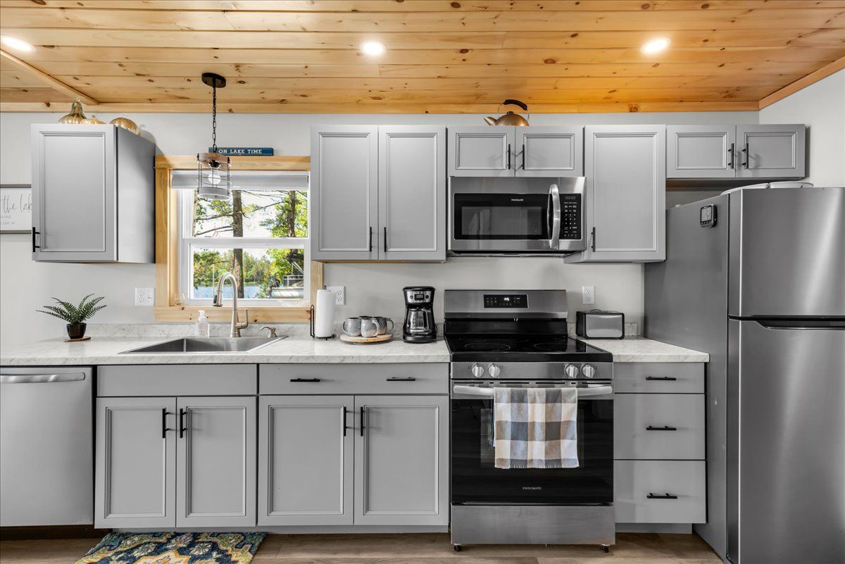 Modern kitchen with gray cabinets, stainless steel appliances, and wood ceiling boards