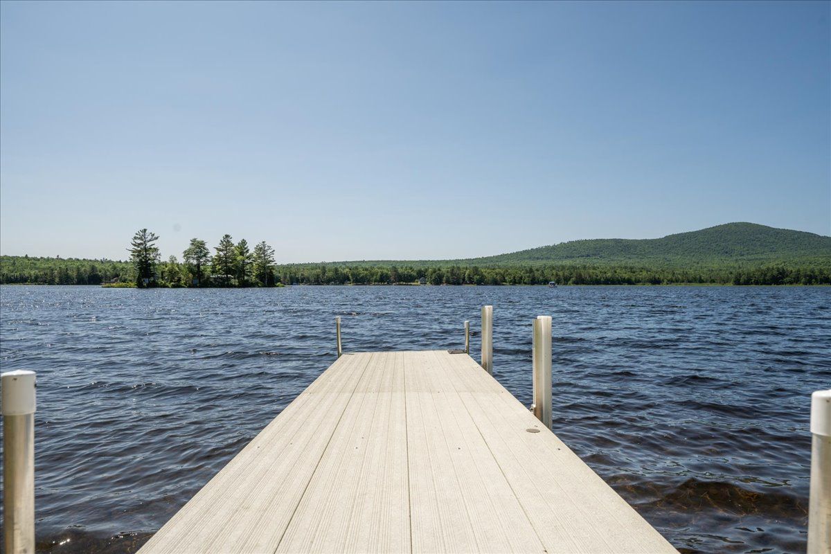 Wooden dock extending into a windy lake with forested shoreline and blue sky