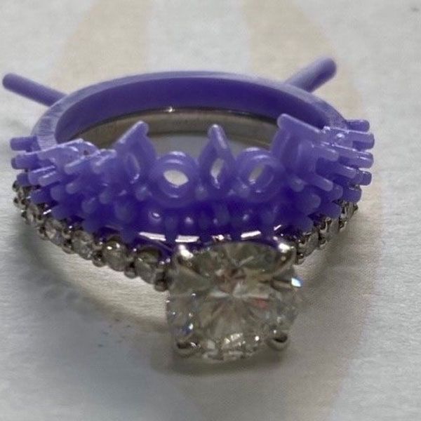 Purple beaded ring with a clear square gemstone on a neutral background