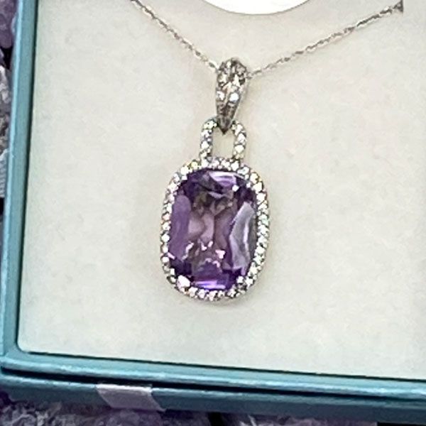 Purple gemstone pendant necklace in a blue jewelry box.