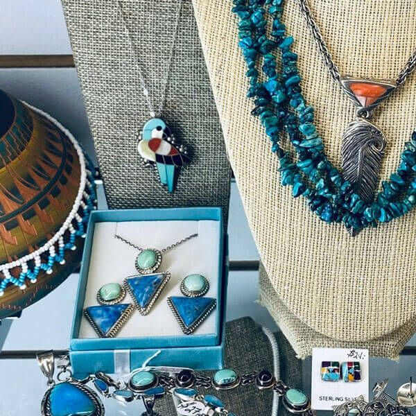 Colorful turquoise and silver jewelry display with necklaces, rings, and earrings on stands and in boxes