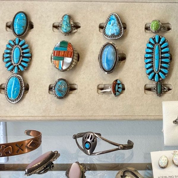 Assorted turquoise and silver rings and jewelry displayed in a case, with a few bracelets below
