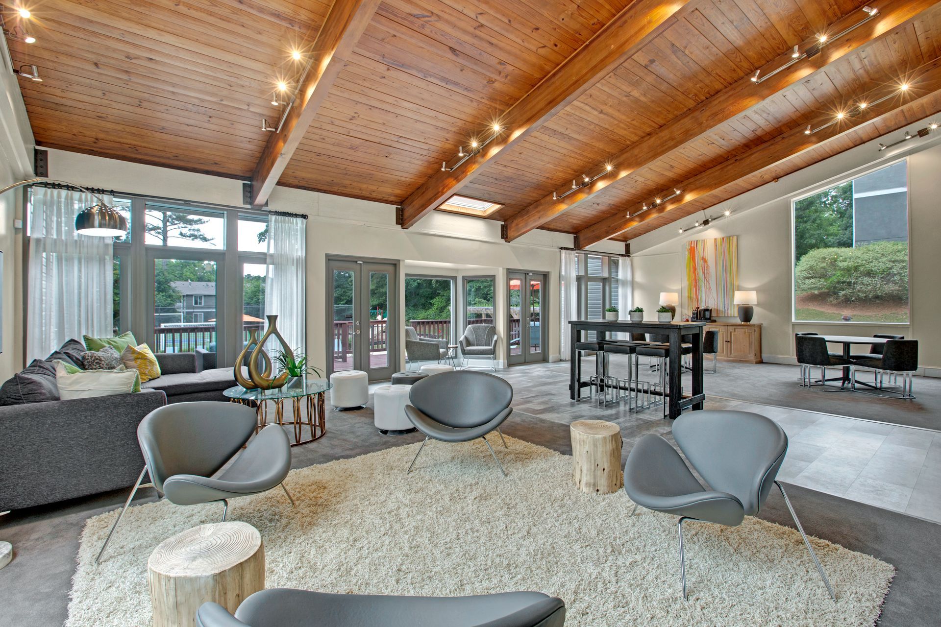 Bright modern living room with wood ceiling, gray chairs, a sofa, and large windows.