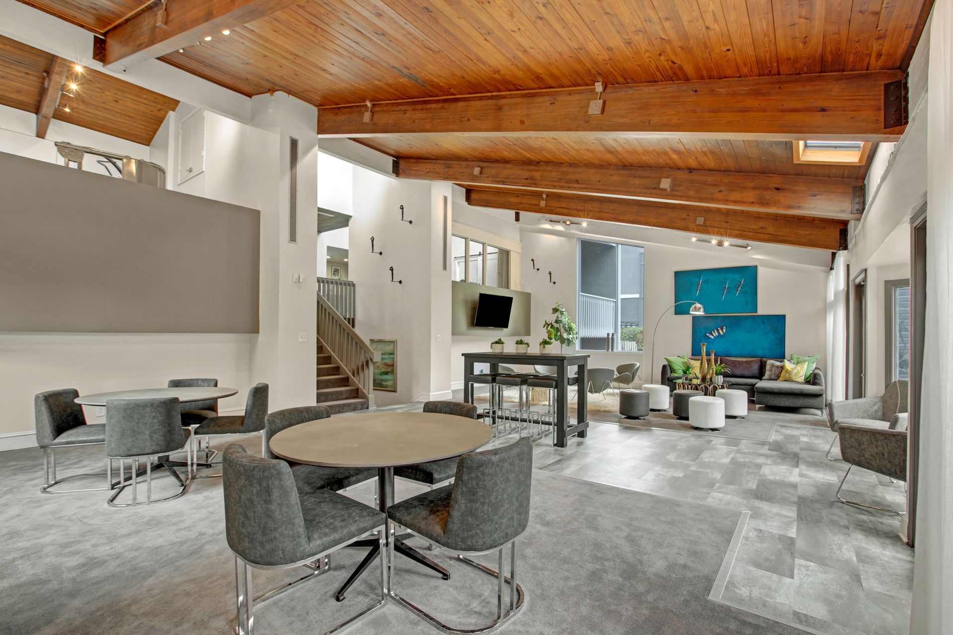 Modern open-plan living space with wood ceiling, gray furniture, kitchen island, and a blue accent wall.