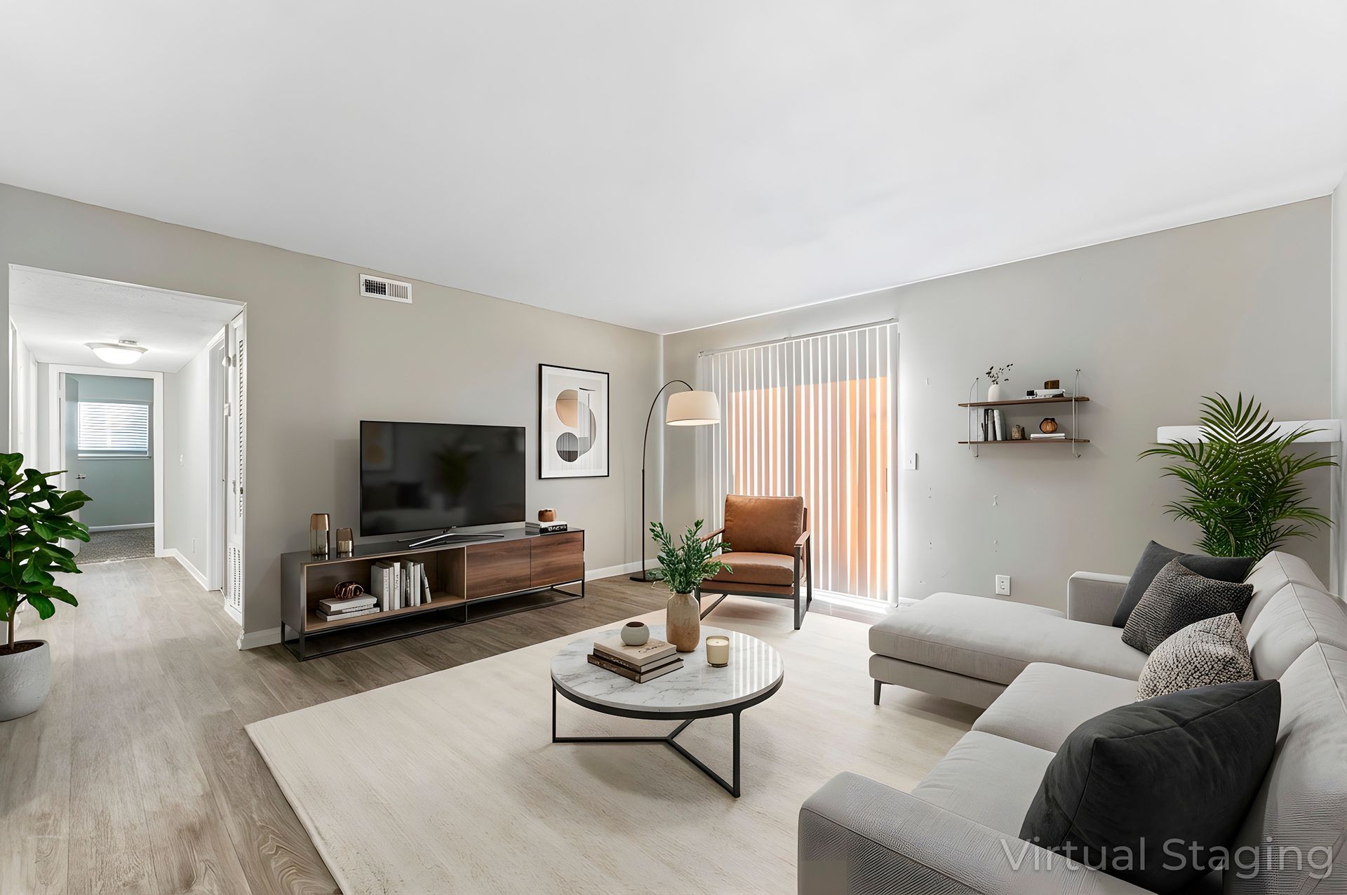 Bright living room with gray sectional sofa, TV console, coffee table, and sliding glass doors to a balcony.