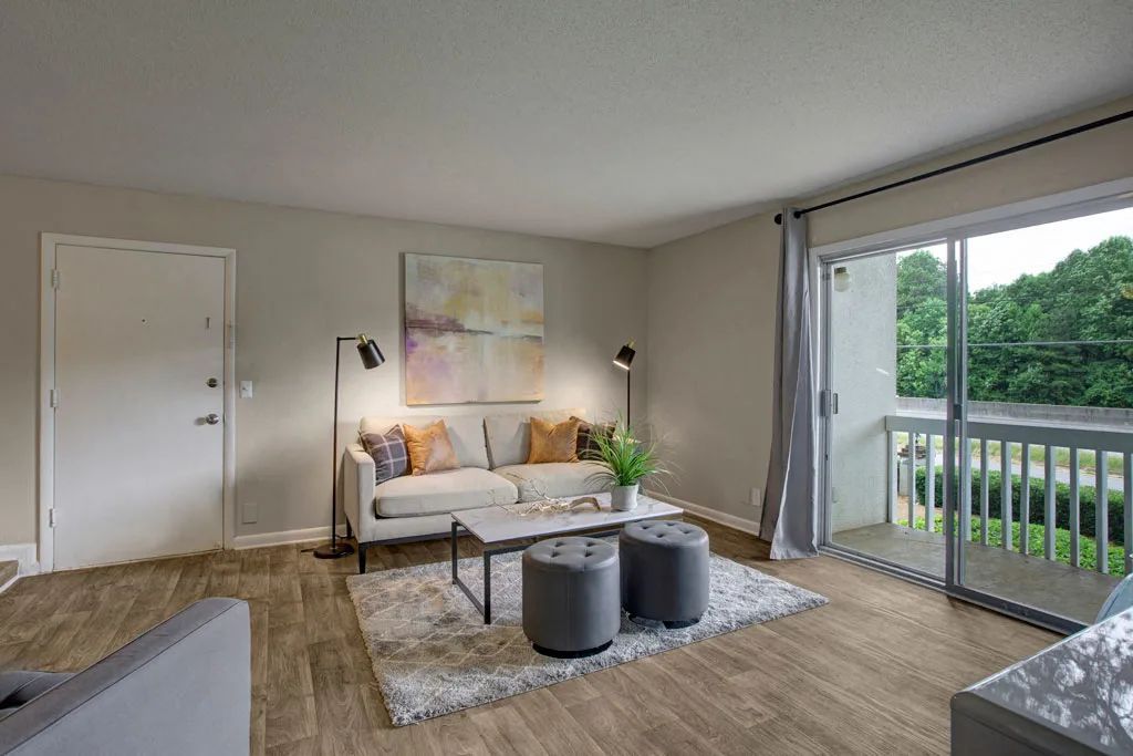 Bright living room with sofa, coffee table, rug, and sliding glass doors opening to a balcony.