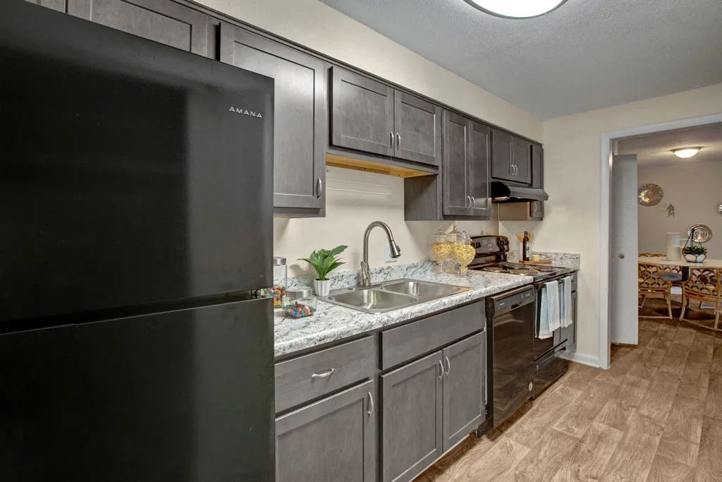 Modern kitchen with dark cabinets, black appliances, and wood-look flooring