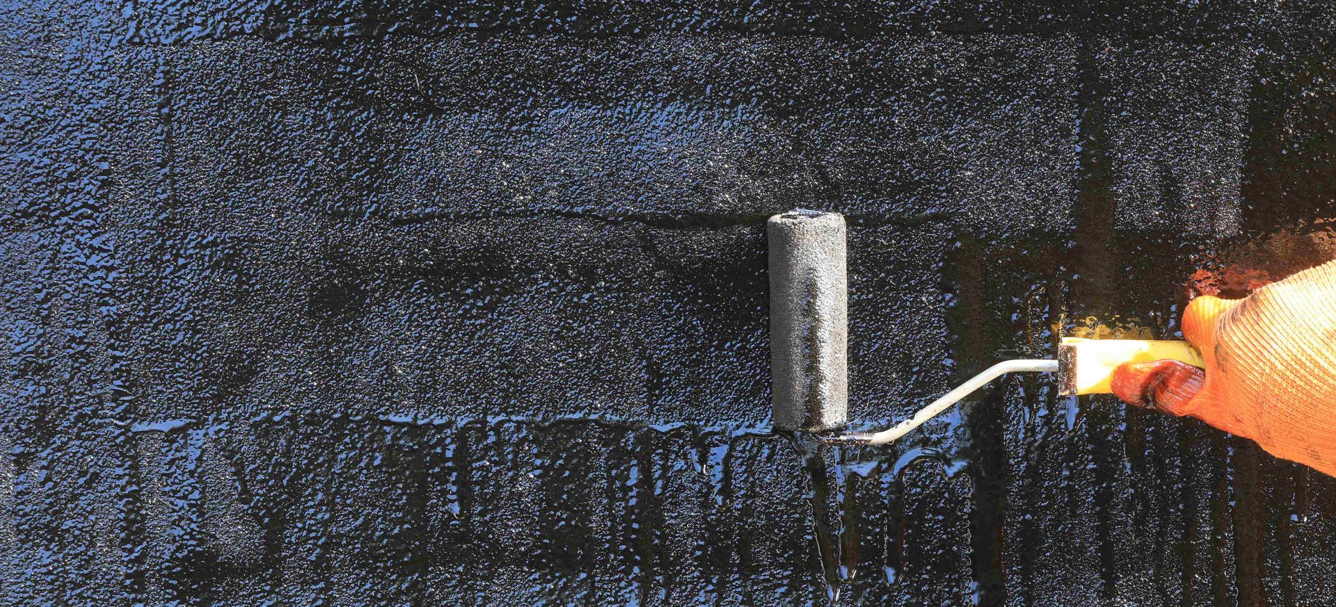 Man waterproofing a concrete wall to protect against heavy rain