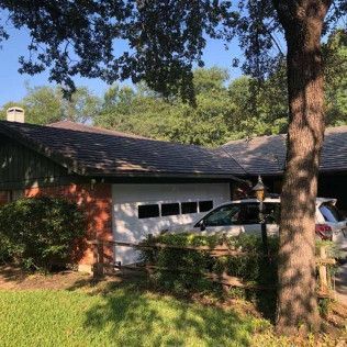 A house with a car parked in front of it and a tree in front of it.