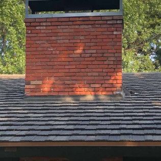 A brick chimney is sitting on top of a roof.