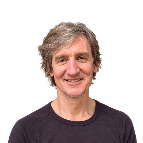 A man wearing glasses and a black shirt smiles for the camera