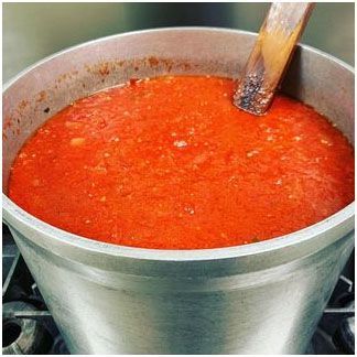 A pot of tomato sauce with a wooden spoon in it