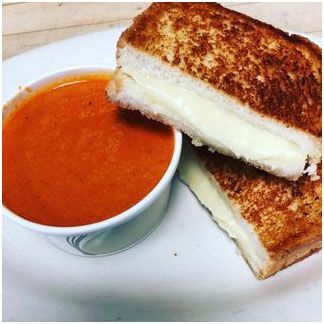 A grilled cheese sandwich and a bowl of tomato soup on a plate