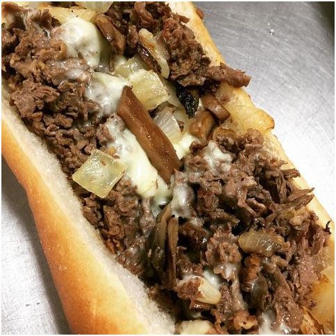 A close up of a cheesesteak sandwich on a bun