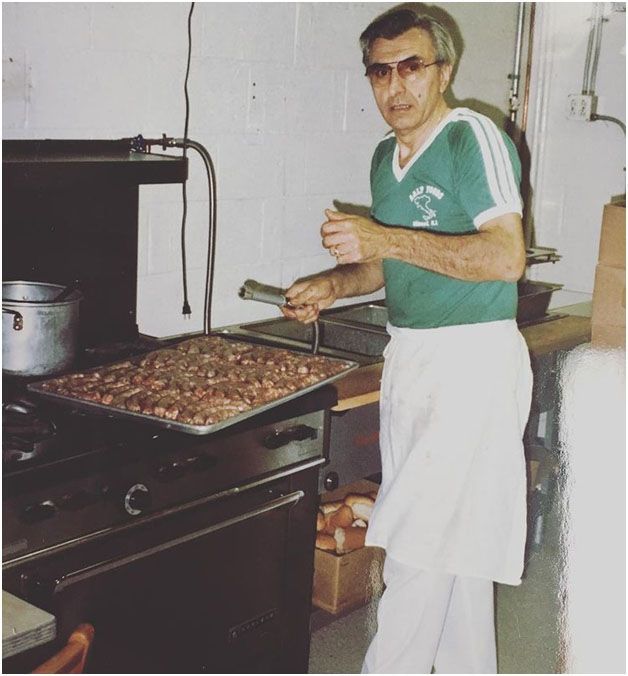 A man wearing a green shirt with the word eagles on it making sausage