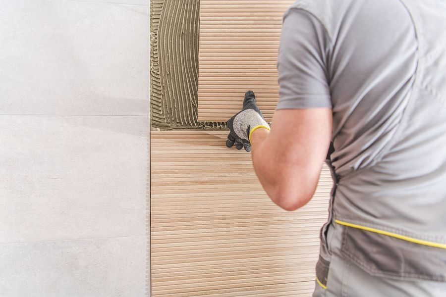 A man is applying adhesive to a tile wall.