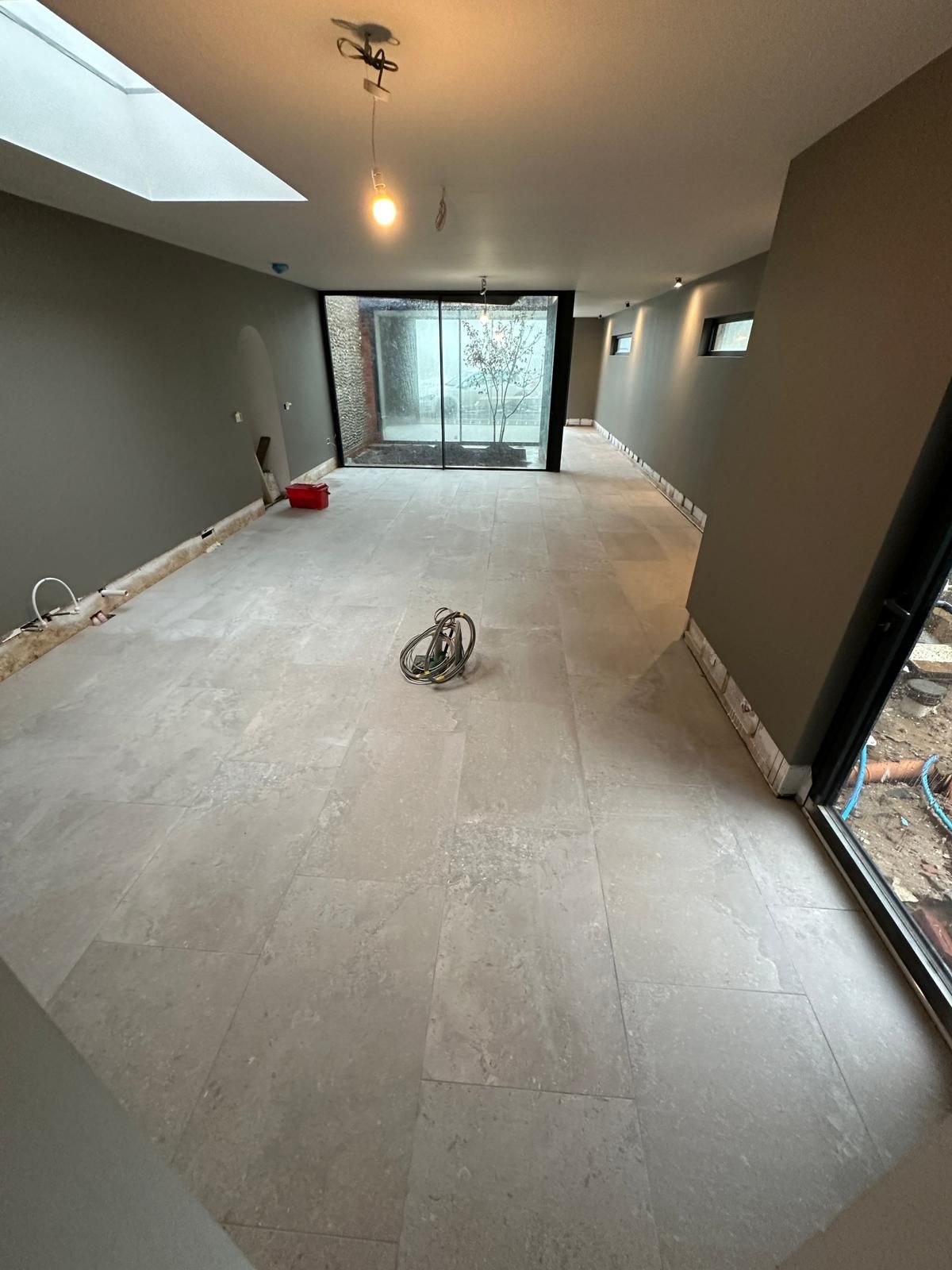 A person is laying a tile floor in a room