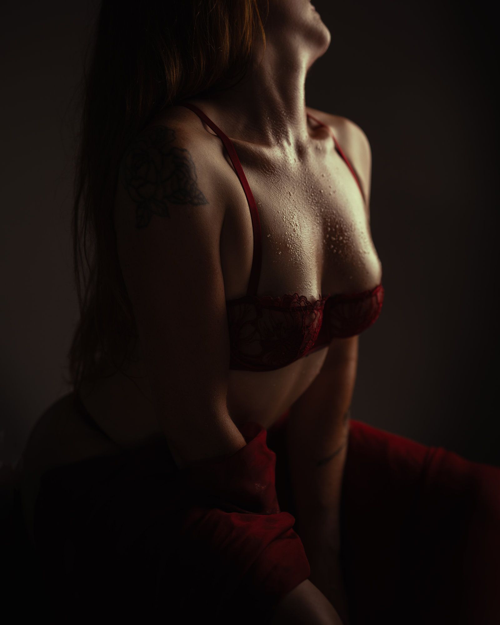 Femme portant de la lingerie blanche, dos à la caméra, tatouages dans le dos, accroupie.