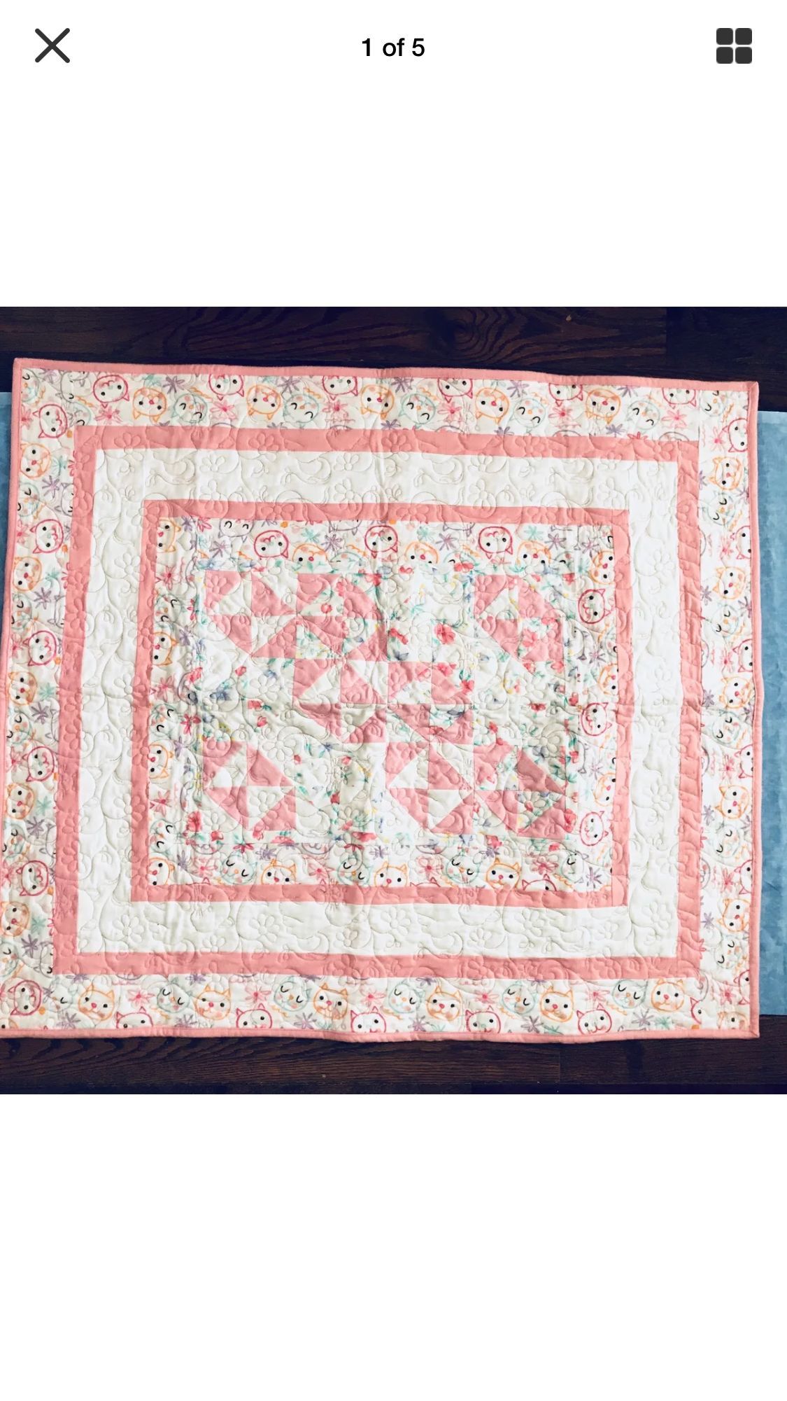 Pink and floral quilt with a square border pattern on a dark background