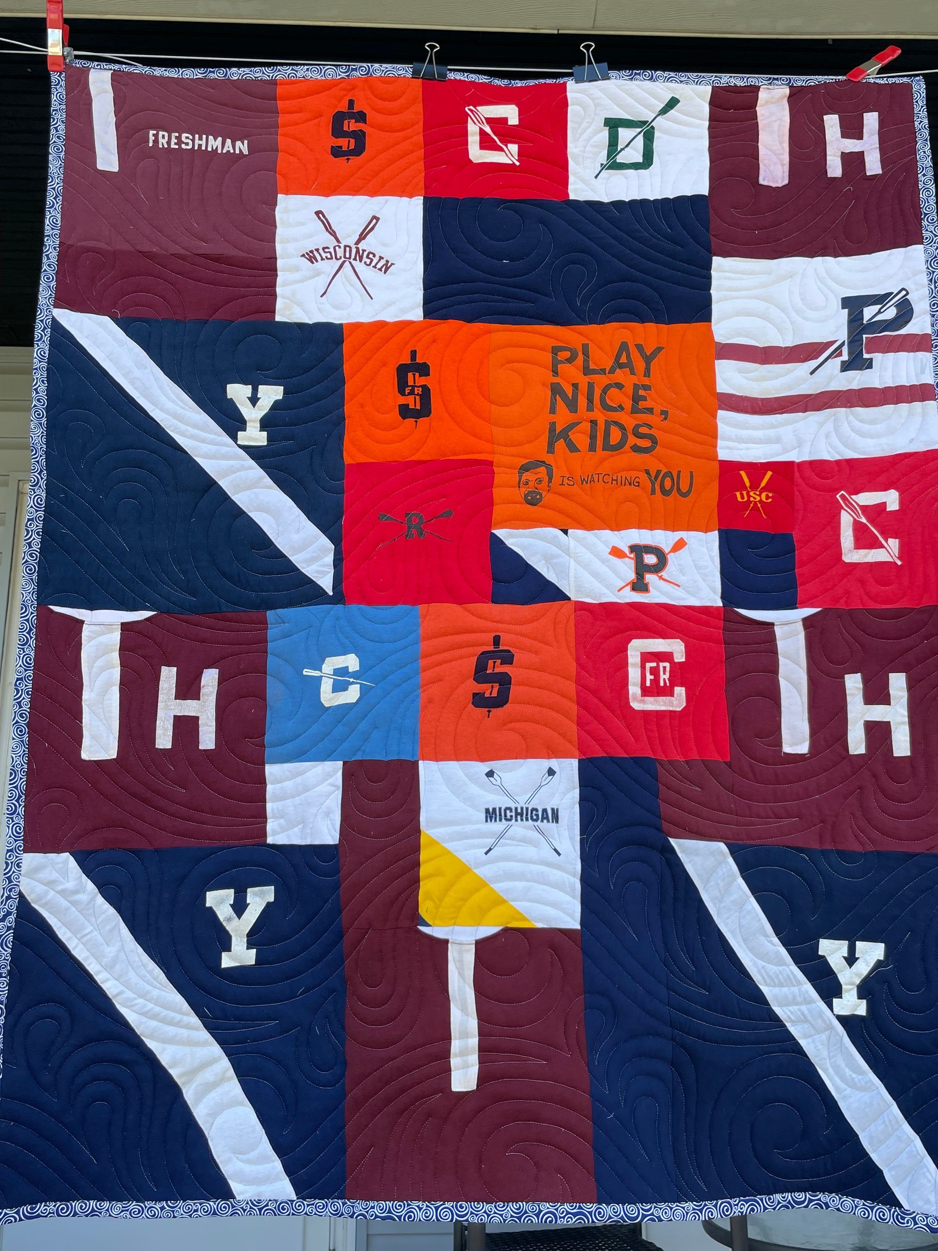 Quilt with red, navy, white, and orange blocks featuring school-themed letters and “Play nice kids” text.