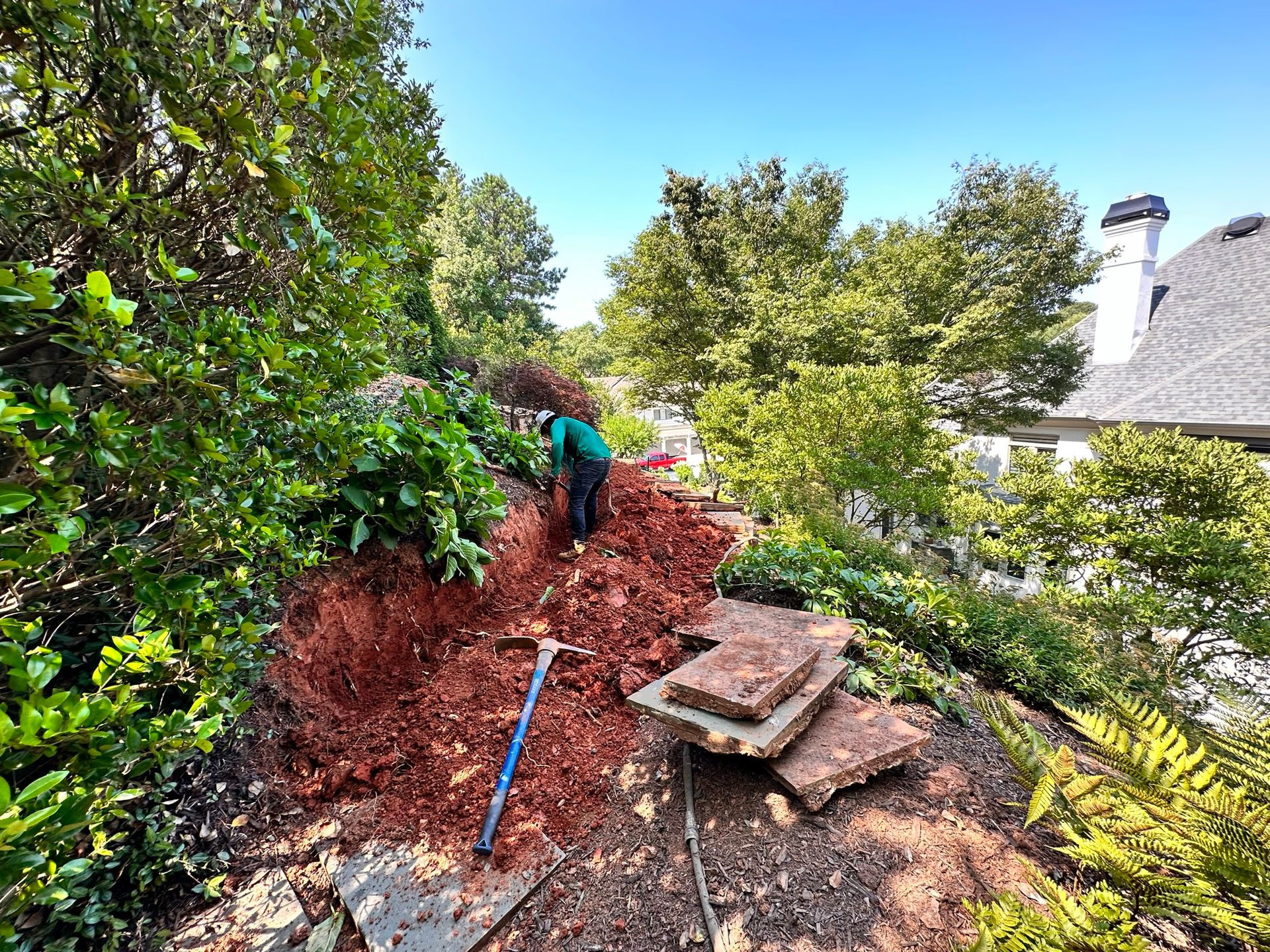 A man is digging in a pile of dirt in a garden.