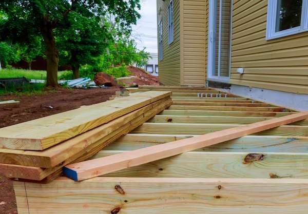 A wooden deck is being built in front of a house.