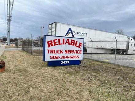 Reliable Truck Service sign beside a white trailer and chain-link fence