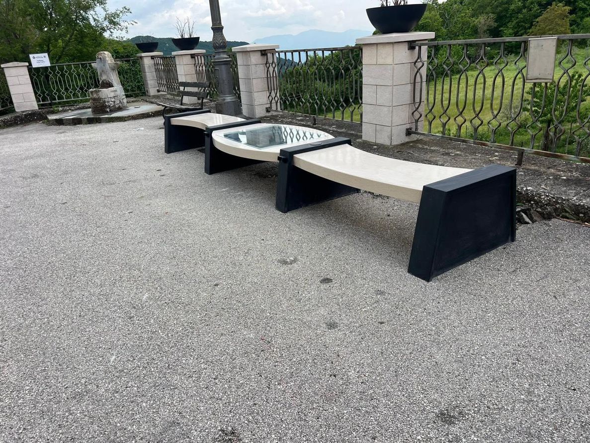 Panchina in pietra da esterno con tavolo in vetro su una terrazza di ghiaia con vista panoramica.