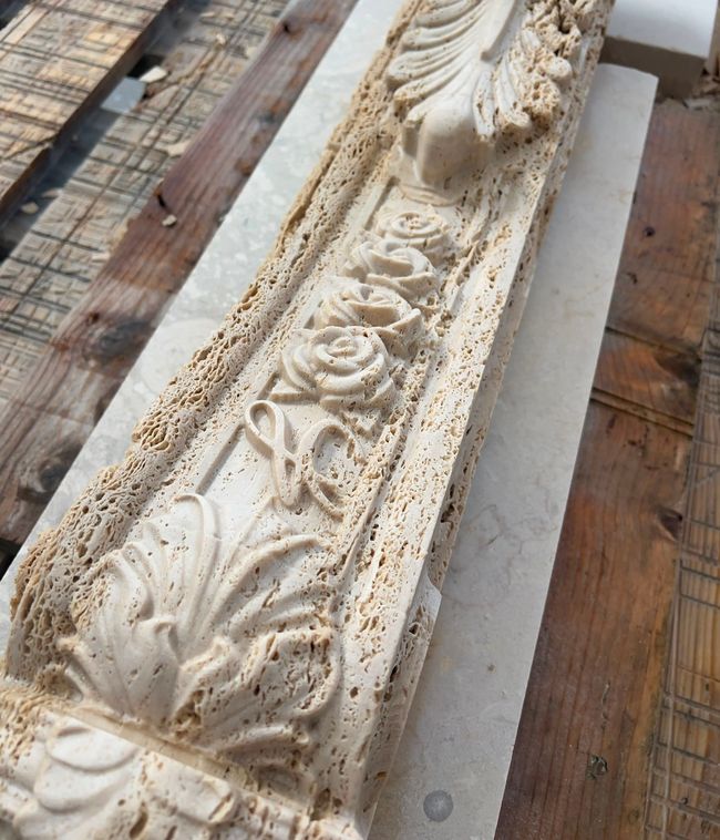 Modanature decorative bianche intagliate con motivi floreali posate su assi di legno per esterni