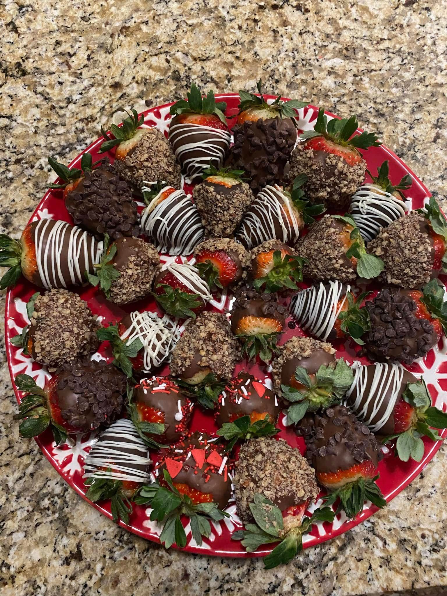 Tray of chocolate-covered strawberries arranged on a red plate on a speckled countertop