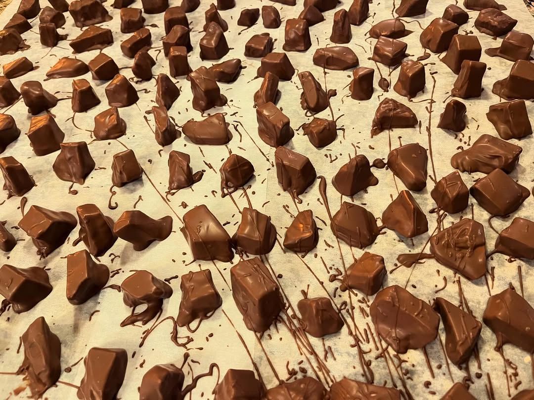 Many small brown chocolate pieces scattered on a creamy white dessert surface