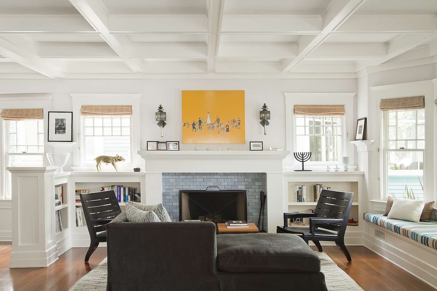 A living room with a fireplace , couch , chairs and a painting on the wall.