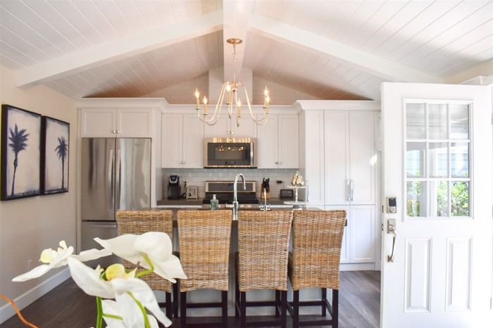 A kitchen with a vaulted ceiling and white cabinets