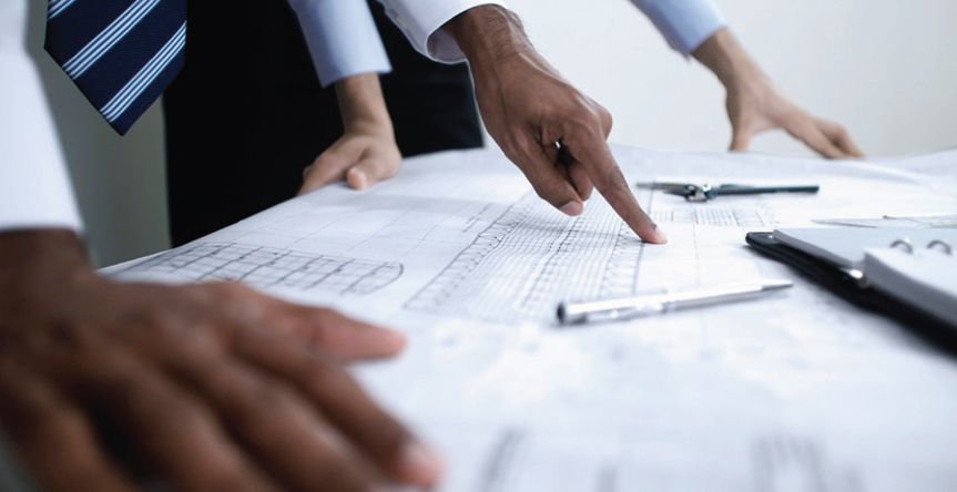 A man is pointing at a piece of paper on a table.