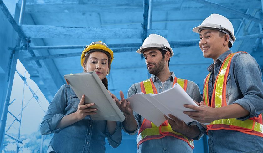 A group of construction workers are looking at a tablet.