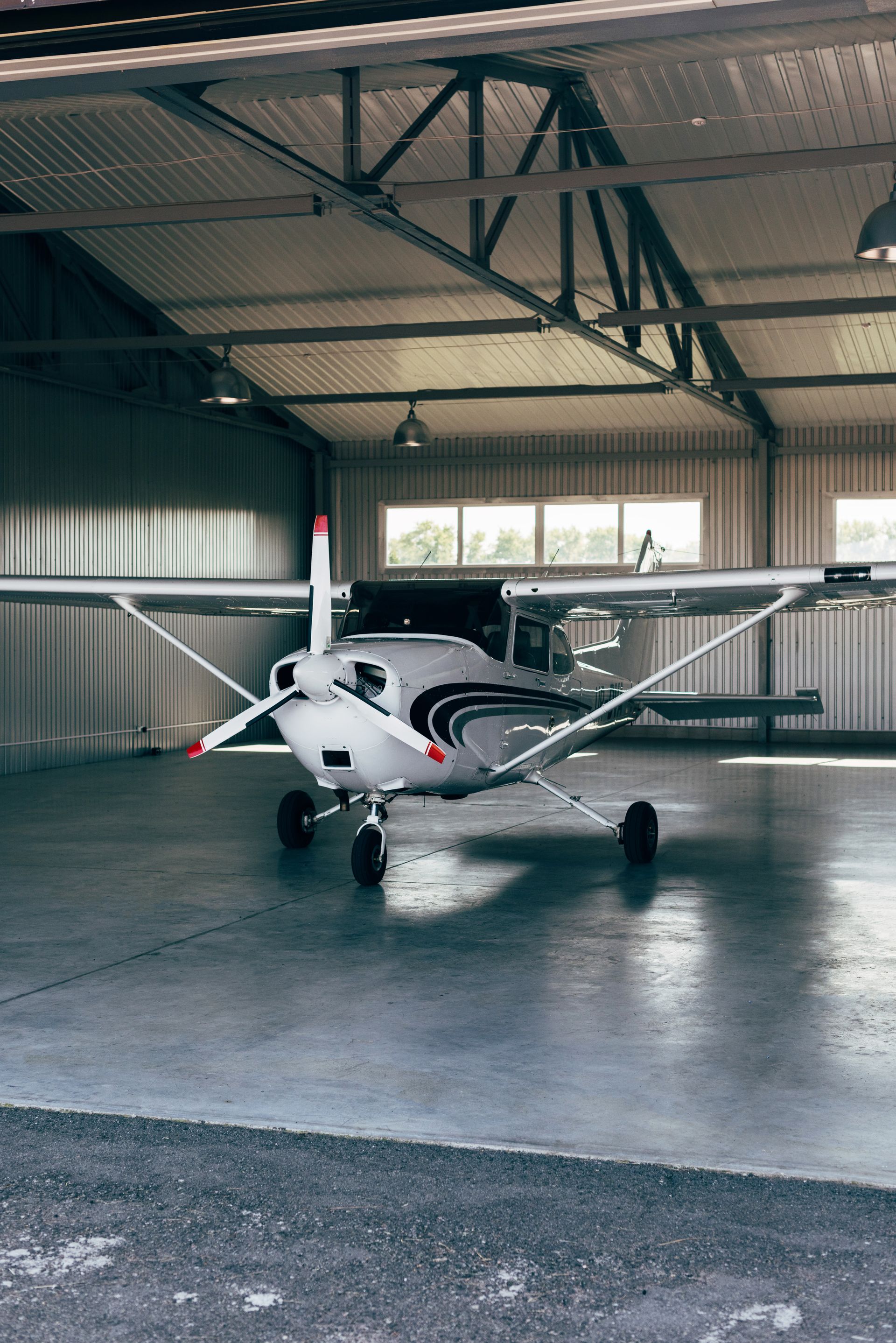 Small white single-engine airplane parked inside a hangar