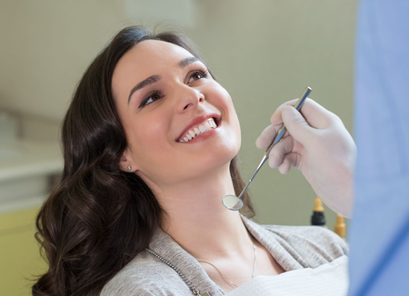 A gloved professional points to a specific area on a panoramic dental X-ray displayed on a screen.