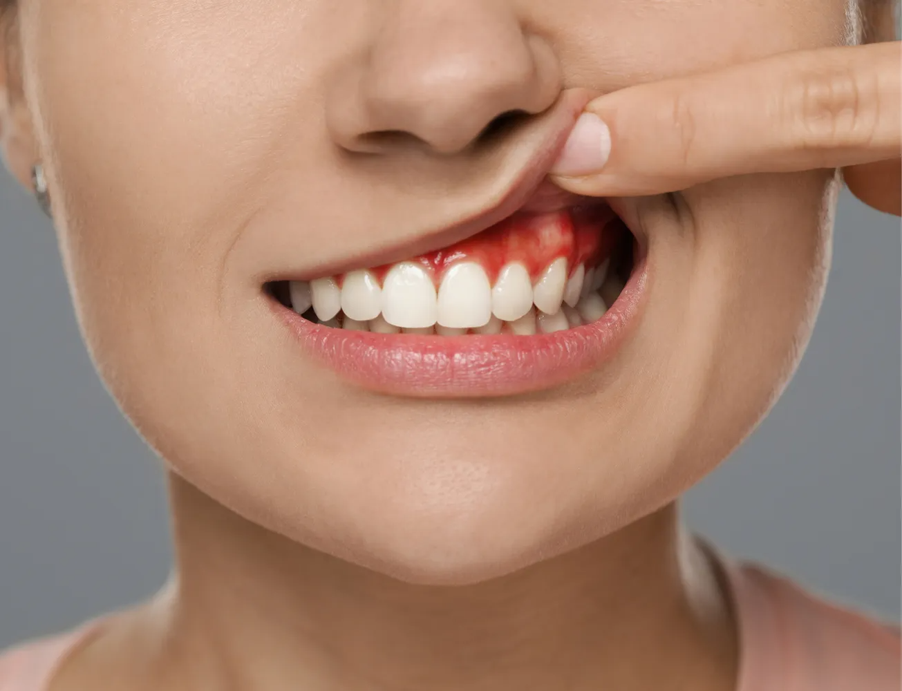 A gloved professional points to a specific area on a panoramic dental X-ray displayed on a screen.