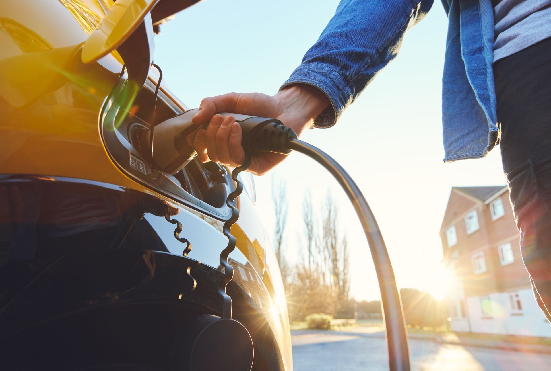 Person fueling a motorcycle at a gas station in bright sunlight