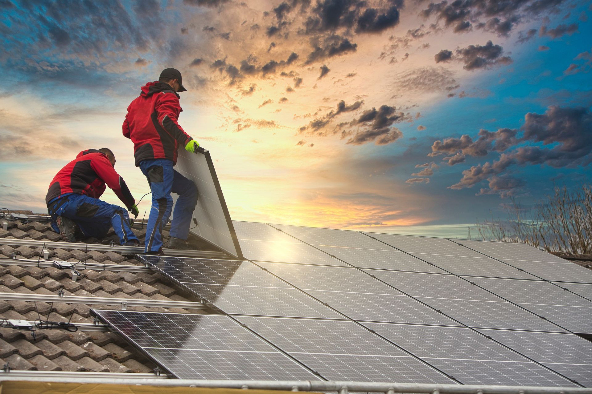 Workers installing solar panels on a rooftop at sunset