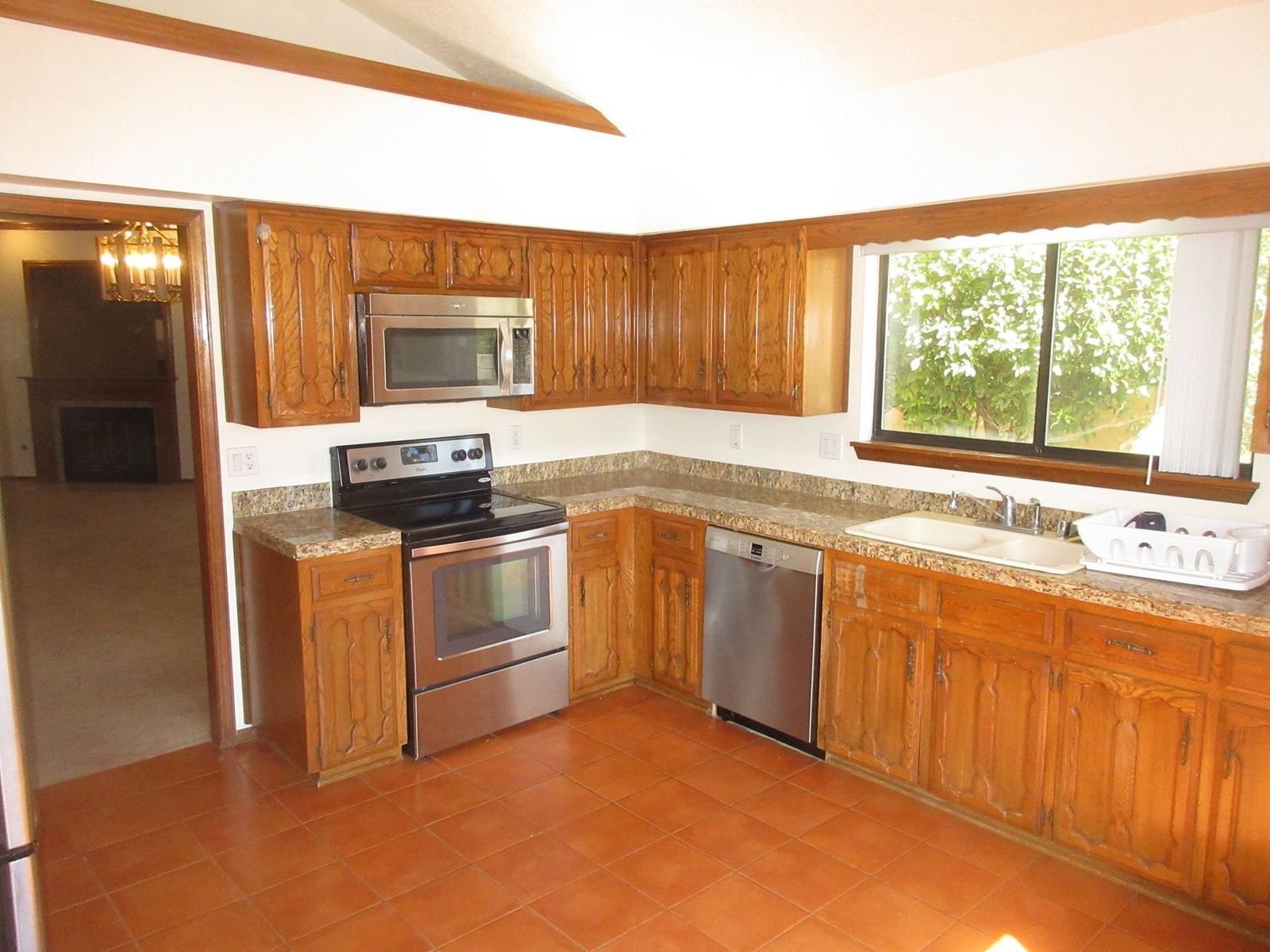 Kitchen with wooden cabinets, stainless steel appliances, and a window.