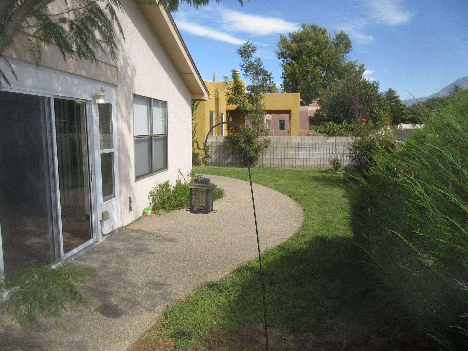 Exterior view: tan house, patio, curved pathway, green grass, and other houses.