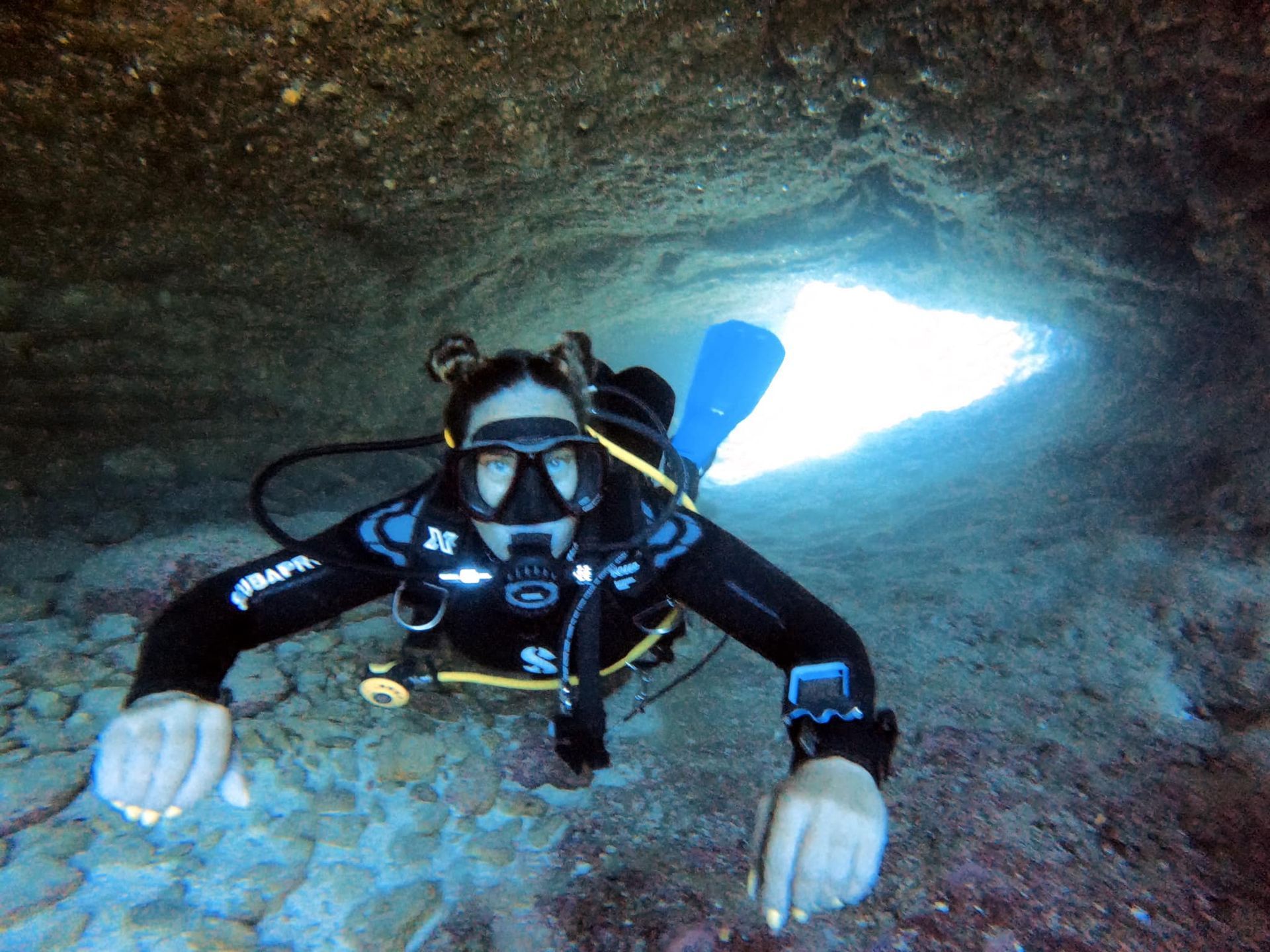 A scuba diver is in a cave with a light coming out of it